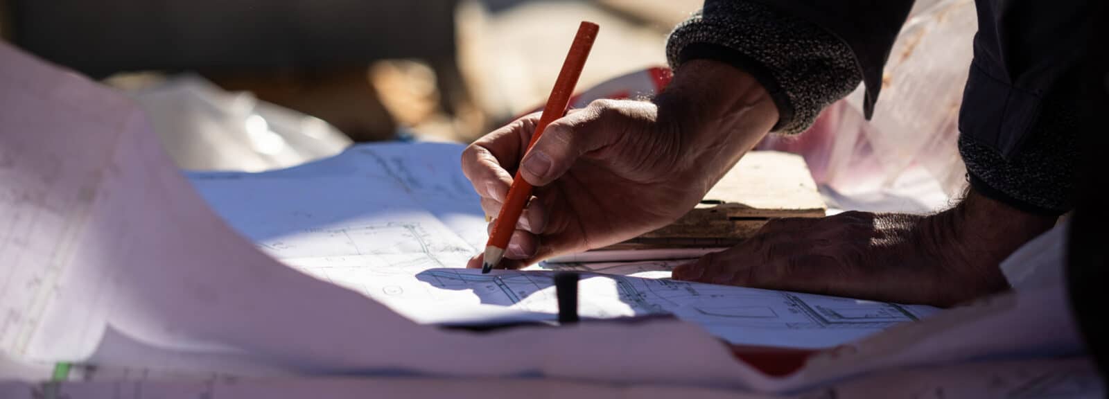 Ein Bauplan wird von Hand mit dem Bleistift ergänzt.